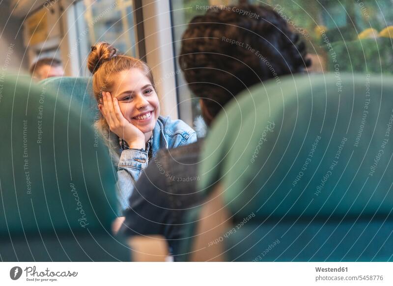 Porträt einer glücklichen jungen Frau, die mit ihrem Freund im Zug reist, London, UK Flirt sitzend sitzt Glück glücklich sein glücklichsein Muße Miteinander