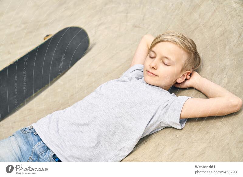 Junge entspannt sich im Skatepark Skateboard Rollbretter Skateboards Buben Knabe Jungen Knaben männlich Entspannung Entspannen relaxen entspannen liegen liegend