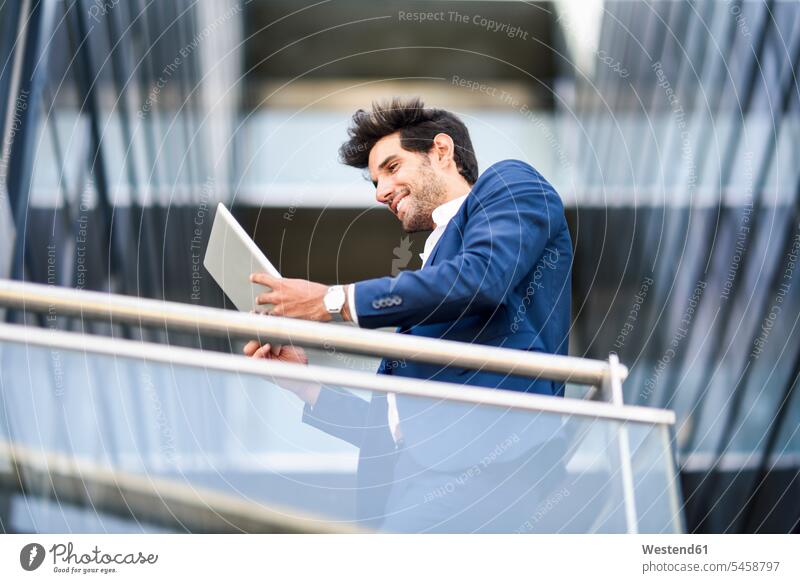 Lächelnder Geschäftsmann mit Tablet auf dem Balkon eines Bürogebäudes Job Berufe Berufstätigkeit Beschäftigung Jobs geschäftlich Geschäftsleben Geschäftswelt