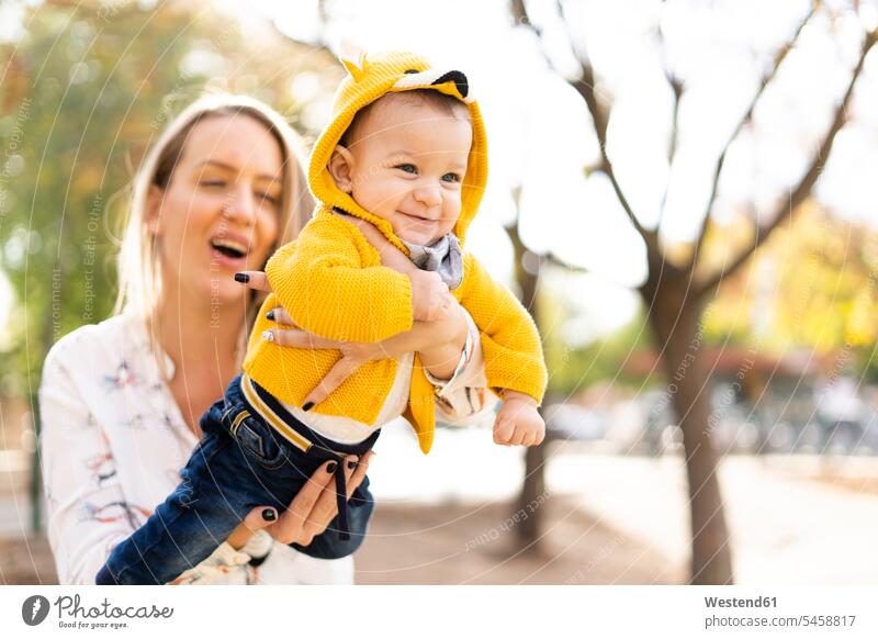 Glückliche Mutter spielt mit kleinem Jungen in einem Park Jacken freuen Frohsinn Fröhlichkeit Heiterkeit behüten behütet geborgen Sicherheit geniessen Genuss