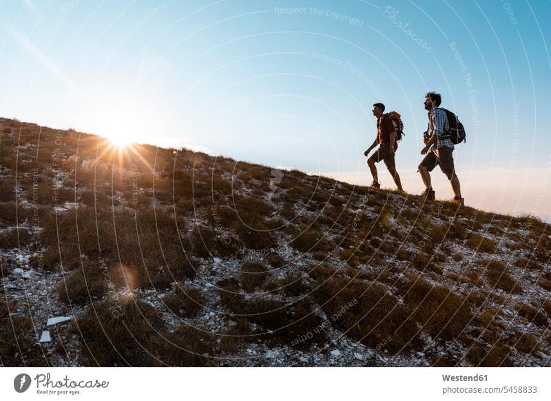 Italien, Monte Nerone, zwei Männer wandern in den Bergen bei Sonnenuntergang Wanderung Mann männlich Sonnenuntergänge Gebirge Berglandschaft Gebirgslandschaft