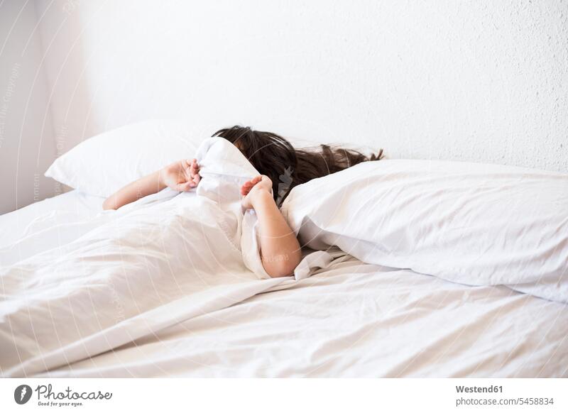 Mädchen im Bett liegend bedeckt ihr Gesicht mit Decke schlafen schlafend weiblich bedecken abdecken zudecken Bettdecke Decken Bettdecken Schlaf Kind Kinder Kids