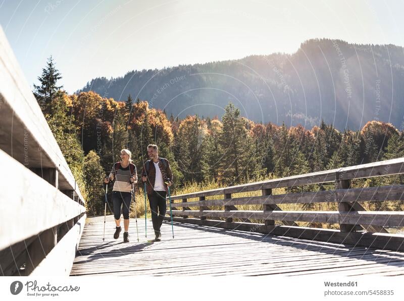 Österreich, Alpen, Paar überquert Brücke beim Wandern mit Wanderstöcken Europäer Europäisch Kaukasier kaukasisch reifer Mann reife Männer 45-50 Jahre