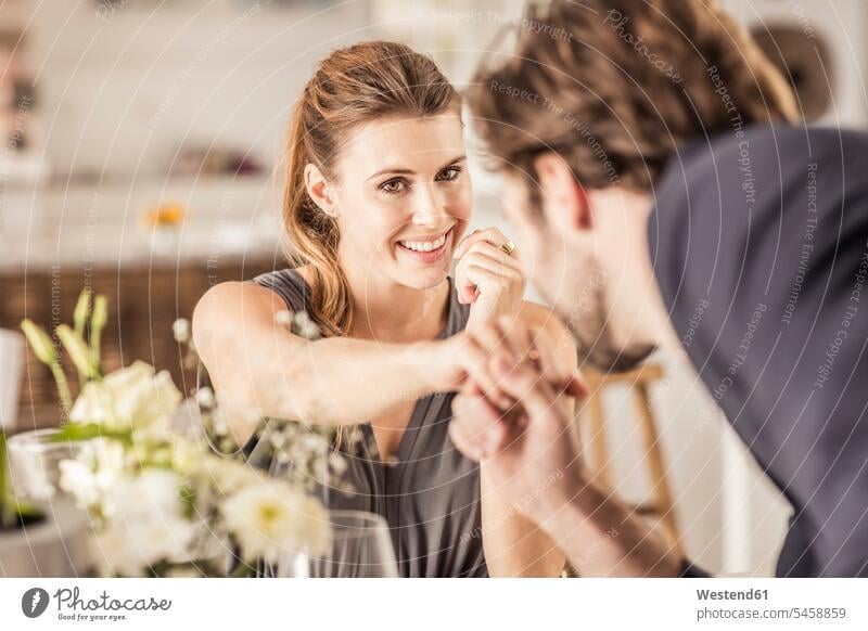 Lächelnde junge Frau sieht ihren Freund an, der ihre Hand küsst Kleider freuen geniessen Genuss Glück glücklich sein glücklichsein gefühlvoll Emotionen