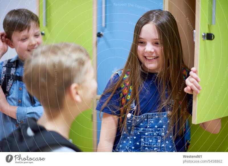 Lächelnde Schüler bei Schließfächern in der Schule Spind lächeln Schulkind Bildung Freizeitkleidung Gruppe Grundschüler Ankunft Freunde Freude Unterhaltung