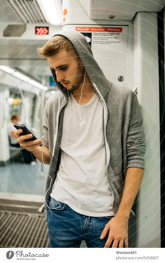 Junger Mann mit Smartphone in der U-Bahn iPhone Smartphones Metro benutzen benützen junger Mann junge Männer Handy Mobiltelefon Handies Handys Mobiltelefone