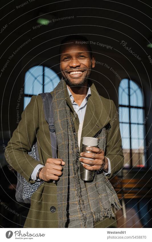 Porträt eines glücklichen stilvollen Mannes mit wiederverwendbarem Becher im Bahnhof geschäftlich Geschäftsleben Geschäftswelt Geschäftsperson Geschäftspersonen