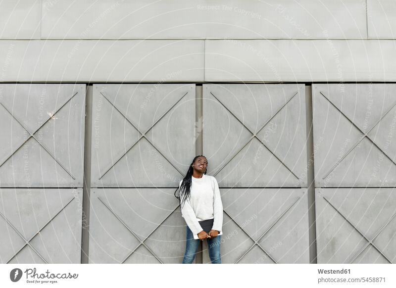 Junge Frau hält eine Tafel an eine graue Wand Farben Farbtoene Farbton Farbtöne grauer graues weiss weiße weißer weißes stehend steht Lifestyles außen draußen