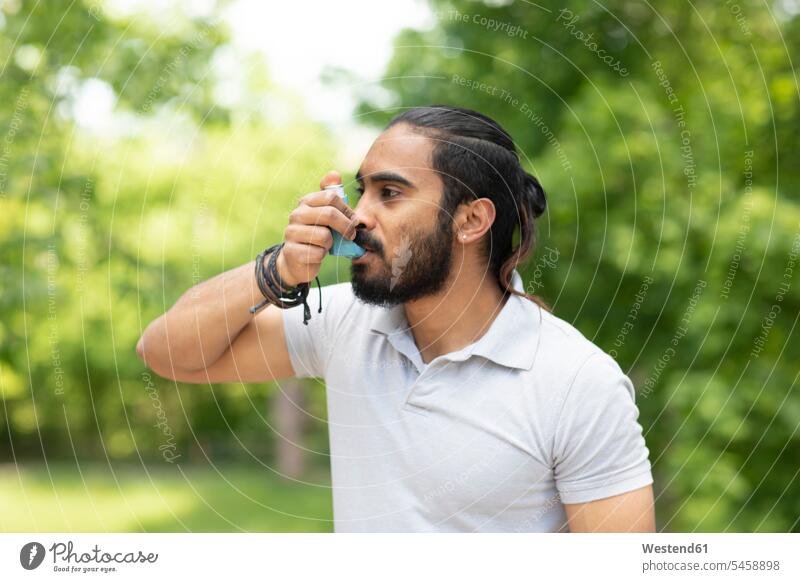 Junger Mann in der Natur mit Asthma-Inhalator Inder indisch indischer indisches Brustbild Oberkörper Haarknoten Dutt Chignons eine Person single 1 ein Mensch