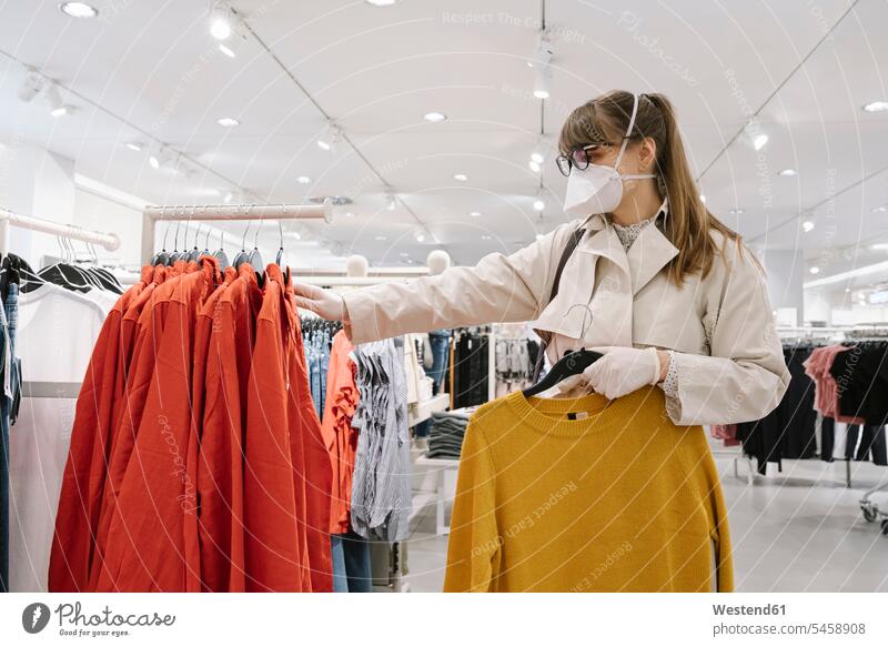 Frau mit Gesichtsmaske und Einweghandschuhen beim Einkaufen in einem Modegeschäft Brillen Kauf shoppen shopping Gesundheit Gesundheitswesen medizinisch