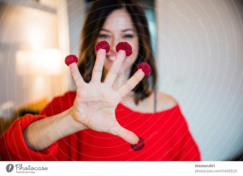 Reife Frau in der Küche stehend, mit Himbeeren auf ihren Fingern Nimm fünf Iss fünf rot rote roter rotes zeigen vorführen präsentieren Vorführung herzeigen