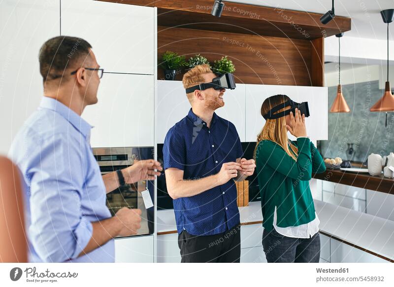 Paar mit VR-Brille beim Einkaufen für eine neue Küche im Showroom Leute Menschen People Person Personen Kunden Kundschaft Job Berufe Berufstätigkeit