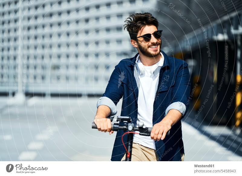 Porträt eines lächelnden Mannes mit Elektroroller im Freien Roller E-Scooter Männer männlich Elektrofahrzeug Erwachsener erwachsen Mensch Menschen Leute People