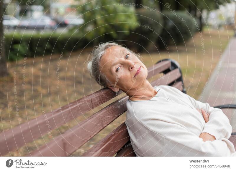Porträt einer älteren Frau, die sich auf einer Bank entspannt Seniorin Seniorinnen alt Sitzbänke Bänke Sitzbank sitzen sitzend sitzt entspanntheit relaxt