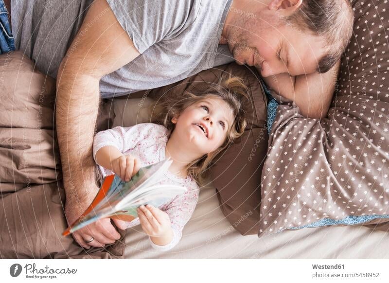Vater und Tochter lesen ein Buch im Bett Bücher Betten Lektüre entspannen relaxen entspanntheit relaxt Glück glücklich sein glücklichsein innig nah zufrieden