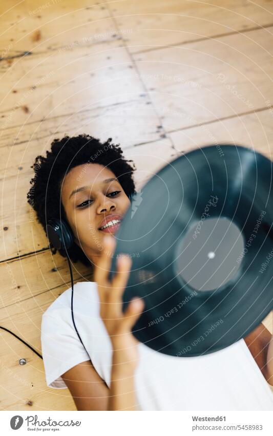 Junge Frau hört zu Hause Vinyl-Schallplatten, liegt am Boden Afroamerikanisch Afro-Amerikanisch Afroamerikaner Afro-Amerikaner dunkelhaarig dunkle Haare