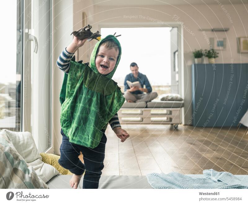 Glücklicher Junge in einem Kostüm spielt mit Spielzeugfigur zu Hause glücklich glücklich sein glücklichsein Maskenkostüm Maskenkostüme Verkleidung Kostüme