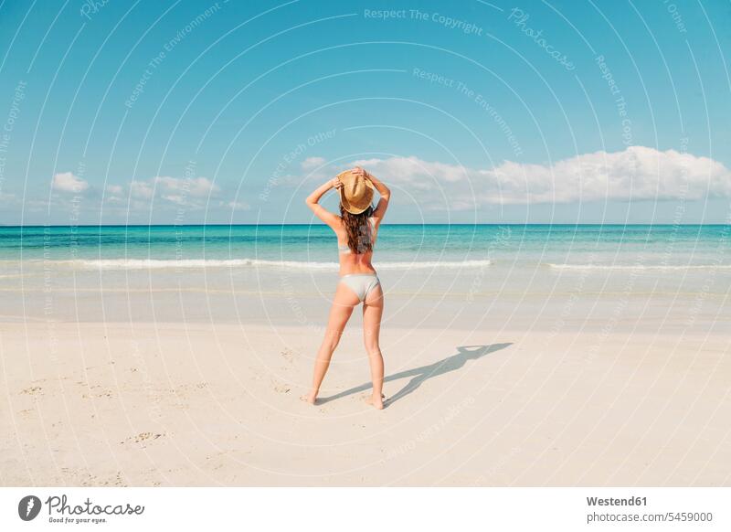 Spanien, Mallorca, Rückansicht einer jungen Frau im Urlaub am Strand stehend Badestrand Badestrände Badestraende Beach Straende Strände Beaches weiblich Frauen