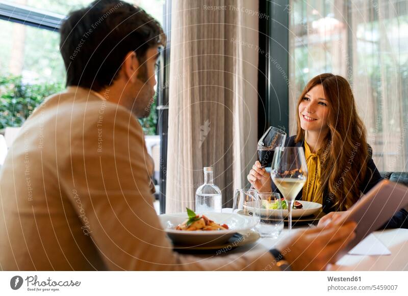 Lächelnde Frau mit Glas Rotwein schaut Mann in einem Restaurant an lächeln trinken ansehen Paar Pärchen Paare Partnerschaft Rotweine Lokal Speiserestaurant