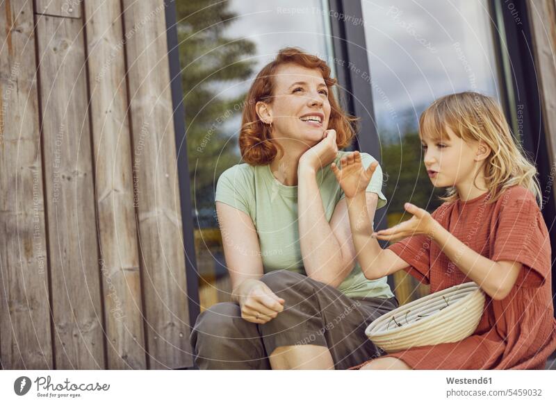 Lächelnde Mutter unterhält sich mit Tochter, während sie vor winzigem Haus sitzt Farbaufnahme Farbe Farbfoto Farbphoto Deutschland Freizeitbeschäftigung Muße
