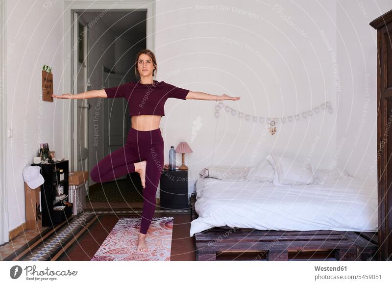 Junge brünette Frau übt Yoga im Studentenwohnheim Betten entspannen relaxen entspanntheit relaxt freuen zufrieden lilafarben violett stehend steht daheim