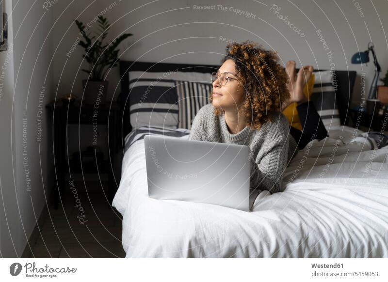 Frau auf dem Bett liegend, mit Laptop, im Internet surfen Laptop benutzen Laptop benützen Zuhause zu Hause daheim Betten liegt Websurfen Im Net surfen Surfen