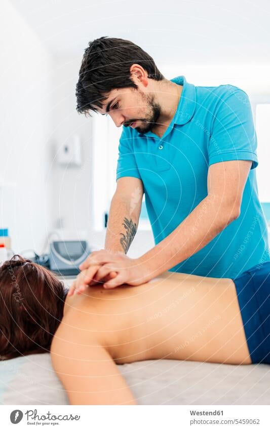 Sehbehinderter männlicher Therapeut massiert den Rücken der Frau in der Klinik Farbaufnahme Farbe Farbfoto Farbphoto Innenaufnahme Innenaufnahmen innen drinnen
