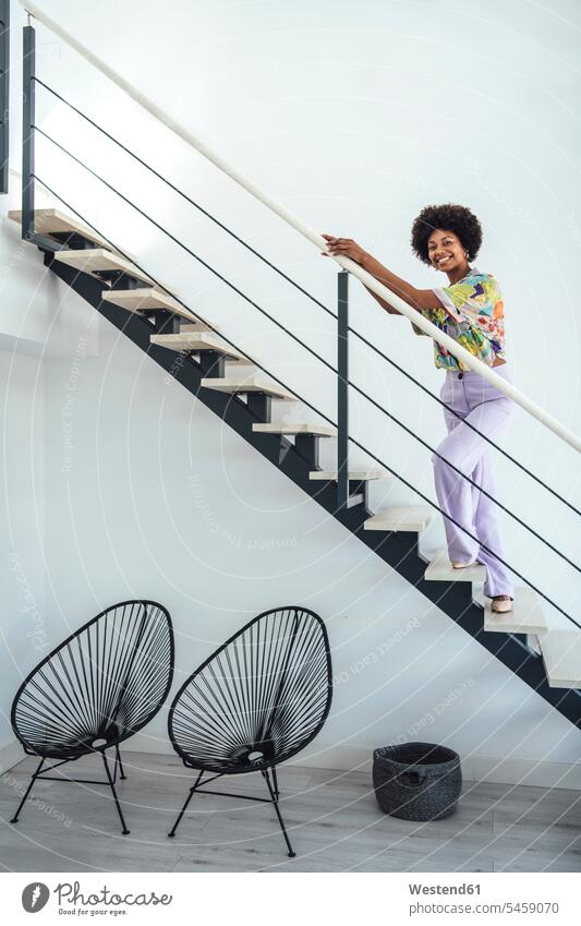 Glückliche Frau steht auf schwebender Treppe in modernem Penthouse Farbaufnahme Farbe Farbfoto Farbphoto Innenaufnahme Innenaufnahmen innen drinnen Tag