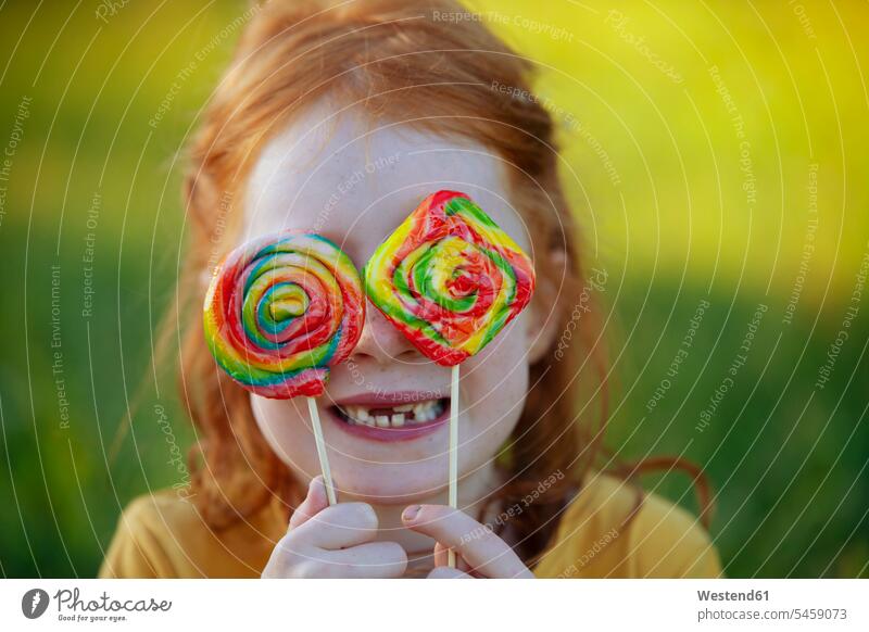 Glückliches Mädchen bedeckt ihre Augen mit Lollipops Lutscher Lollis Dauerlutscher Portrait Porträts Portraits weiblich bedecken abdecken zudecken Süßigkeiten