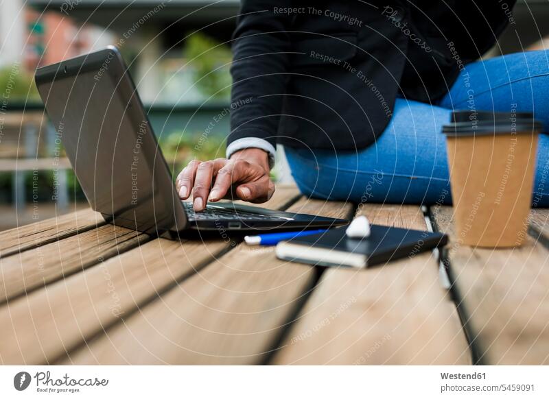 Geschäftsfrau sitzt auf einem Tisch im Freien und benutzt einen Laptop, Teilansicht Geschäftsfrauen Businesswomen Businessfrauen Businesswoman Tische Notebook