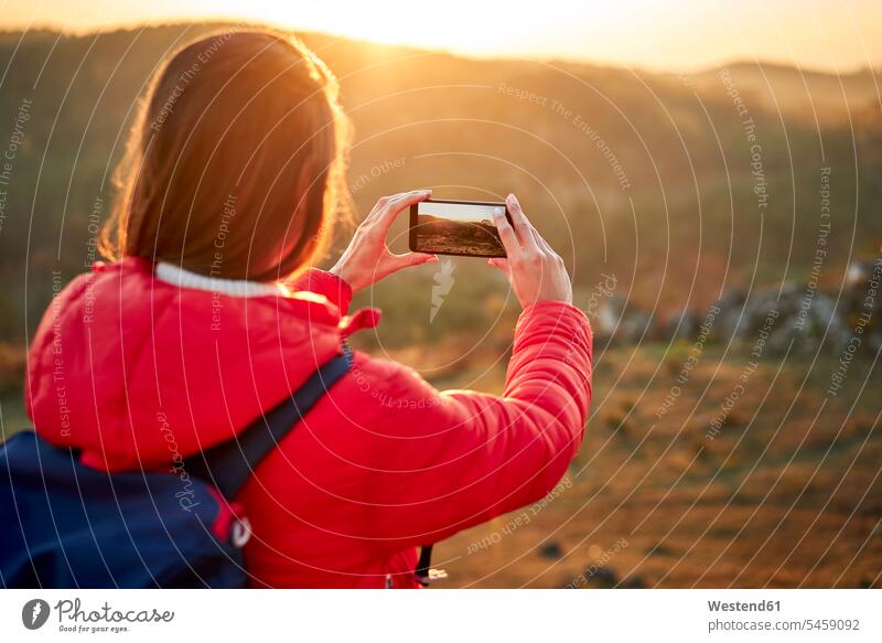 Frau auf einem Wanderausflug nimmt Smartphone Foto bei Sonnenuntergang wandern Wanderung Sonnenuntergänge weiblich Frauen Gebirge Berglandschaft