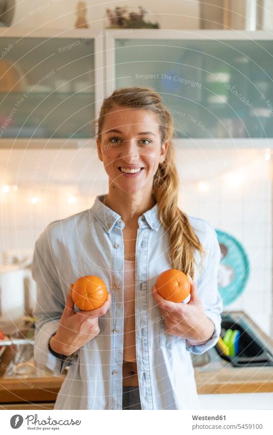 Porträt einer glücklichen jungen Frau, die zu Hause Orangen hält Leute Menschen People Person Personen Alleinstehende Alleinstehender Singles Unverheiratete