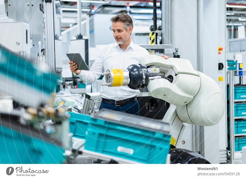 Geschäftsmann mit Tablet am Montageroboter in einer Fabrik Job Berufe Berufstätigkeit Beschäftigung Jobs geschäftlich Geschäftsleben Geschäftswelt