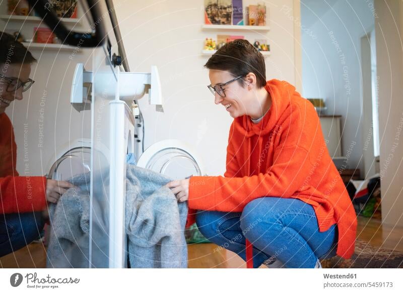 Junge Frau macht die Wäsche zu Hause junge Frau junge Frauen Hausarbeit Hausarbeiten Küche Küchen Zuhause daheim Waschmaschine Waschmaschinen waschen weiblich
