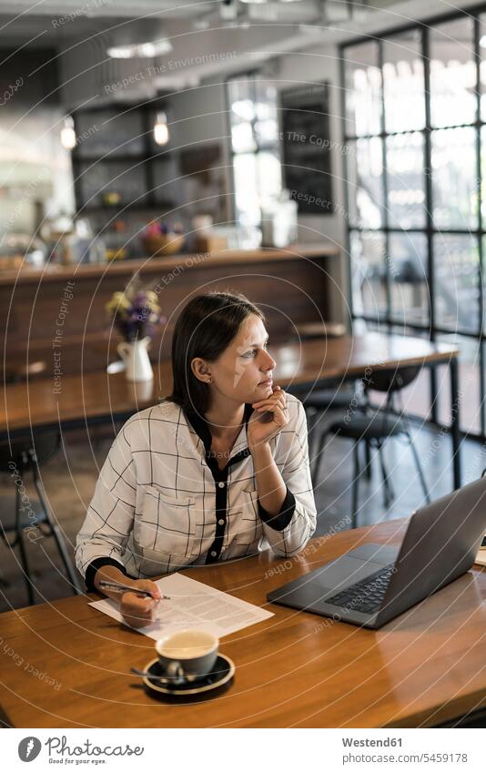 Junge Geschäftsfrau in einem Café schreiben auf Papier und arbeiten mit Laptop auf Holztisch Holztische Arbeit Papiere Notebook Laptops Notebooks aufschreiben
