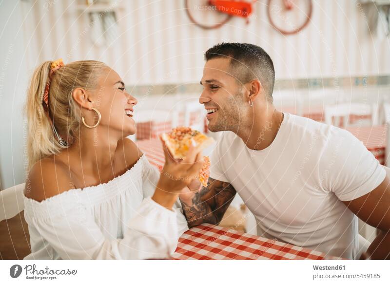 Glückliches junges Paar isst Pizza, während es im Restaurant sitzt Farbaufnahme Farbe Farbfoto Farbphoto Spanien Freizeitbeschäftigung Muße Zeit Zeit haben
