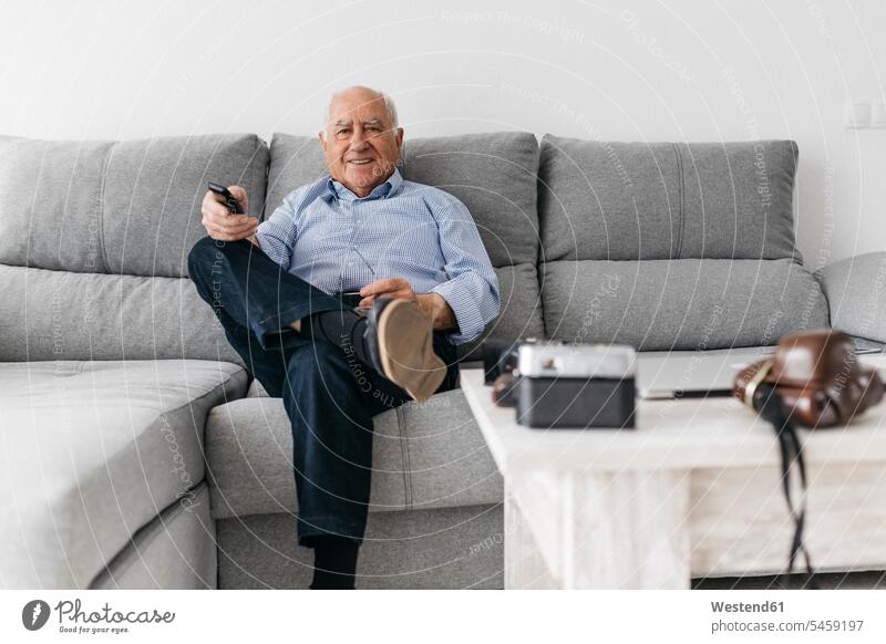 Älterer Mann sieht zu Hause von der Couch aus fern Sofa Couches Liege Sofas Senior ältere Männer älterer Mann Senioren Hobby Hobbies fernsehen Fernbedienung