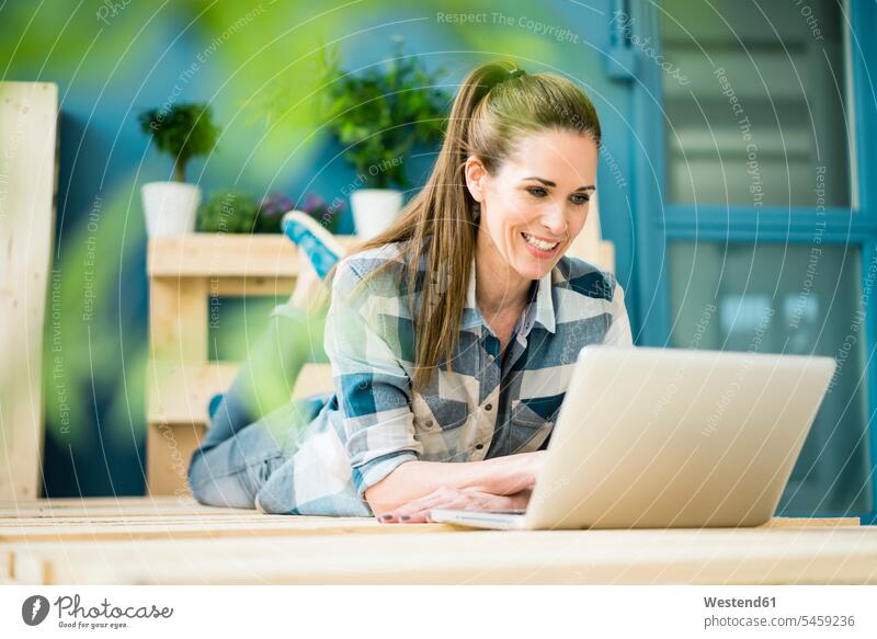 Lachende Frau mit Laptop in der neuen Wohnung Palette Paletten Transportpaletten Notebook Laptops Notebooks renovieren Renovierung wohnen Wohnungen Heimwerkerin
