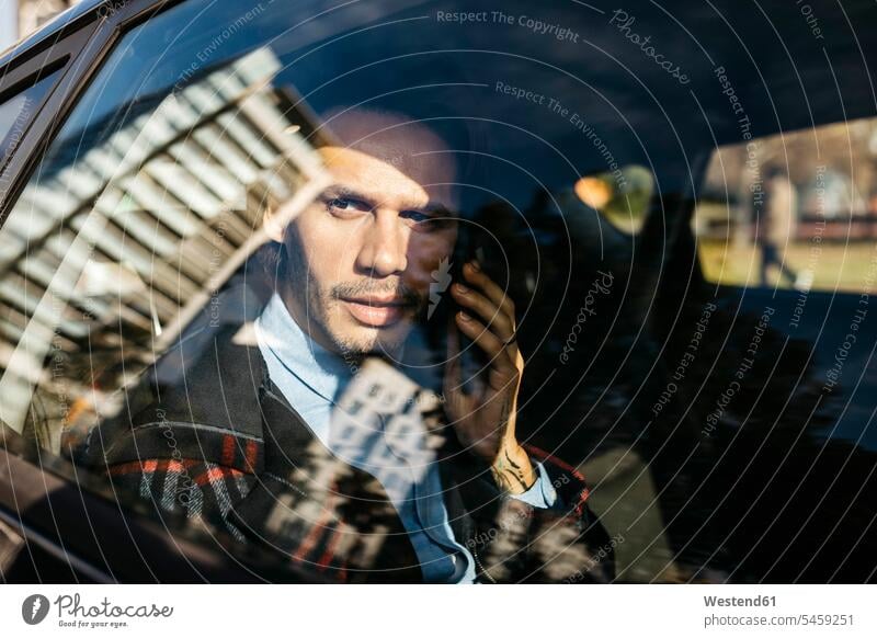 Mann sitzt auf dem Rücksitz eines Autos und spricht mit einem Mobiltelefon telefonieren anrufen Anruf telephonieren Wagen PKWs Automobil Handy Handies Handys