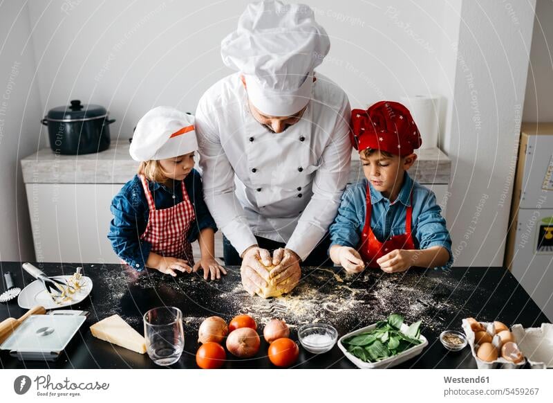 Vater mit zwei Kindern bereitet zu Hause in der Küche selbstgemachte glutenfreie Nudeln zu Gastronomie Koeche Kuechenchef Kuechenchefs Köche Küchenchef
