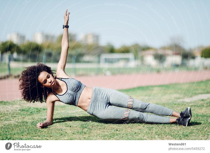 Sportliche junge Frau macht Seite Planken auf Rasen Side-Plank Seitenstütz Seitenstützen sportlich weiblich Frauen Erwachsener erwachsen Mensch Menschen Leute