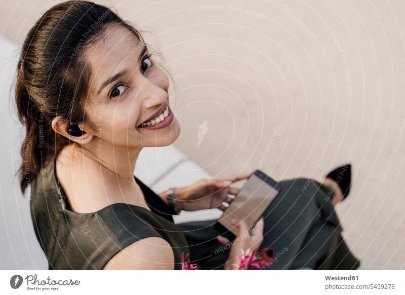 Nahaufnahme einer lächelnden berufstätigen Frau, die ein Mobiltelefon benutzt, während sie auf einem Sitz sitzt Farbaufnahme Farbe Farbfoto Farbphoto Spanien