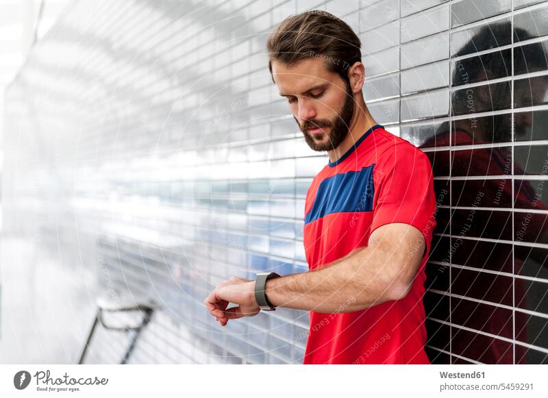 Mann macht eine Pause vom Laufen und überprüft die Zeit auf einer Smartwatch Männer männlich checken Erwachsener erwachsen Mensch Menschen Leute People Personen