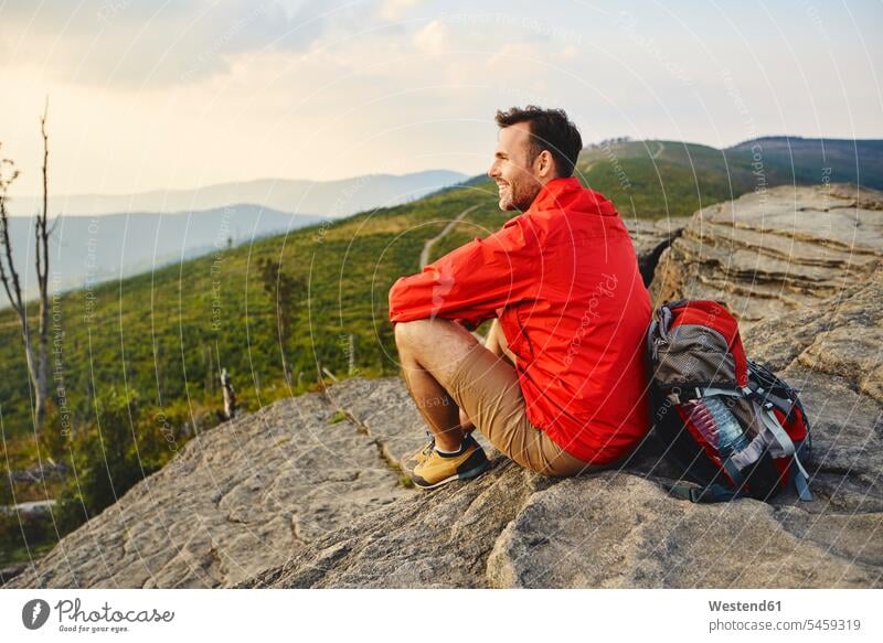 Mann sitzt auf einem Felsen und genießt die Aussicht während einer Wanderung genießen geniessen Genuss Ausblick Ansicht Überblick Männer männlich Berg Berge
