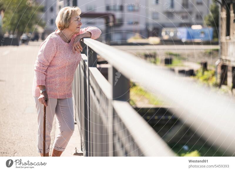 Ältere Frau, die auf einer Fußgängerbrücke geht, mit Gehstock gehend freuen Glück glücklich sein glücklichsein Erwartung sehnsüchtig Streben zufrieden Farben