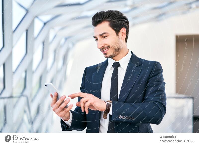 Lächelnder Geschäftsmann schaut auf Handy Mobiltelefon Handies Handys Mobiltelefone ansehen Businessmann Businessmänner Geschäftsmänner lächeln Telefon
