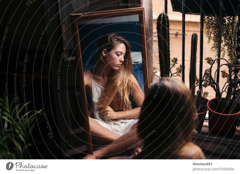 Spiegelbild der jungen Frau sitzt auf dem Boden zu Hause entspannen Entspannung relaxen Spiegelbilder weiblich Frauen sitzen sitzend Fußboden Fußboeden