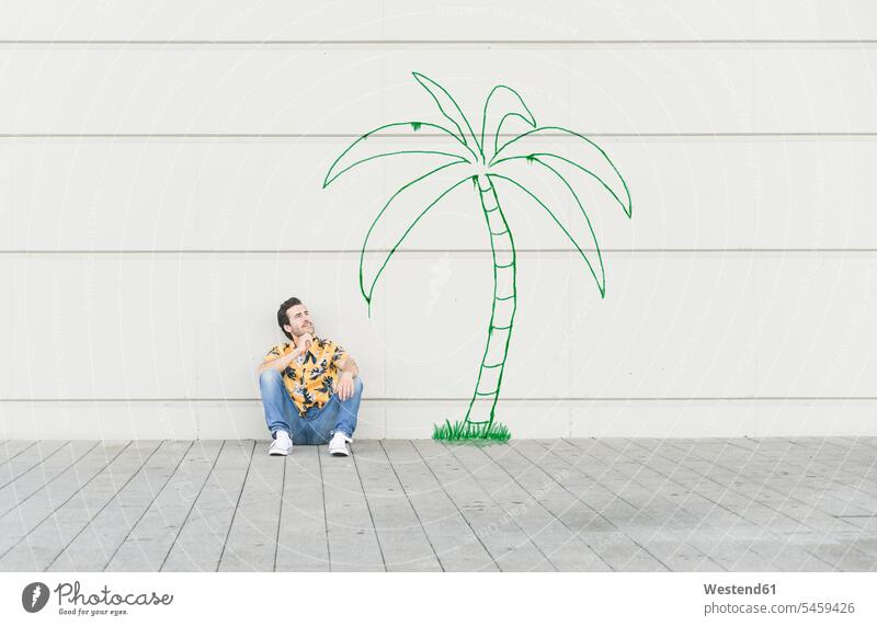 Digitales Komposit eines jungen Mannes, der an einer Palme an einer Wand sitzt Leute Menschen People Person Personen Europäisch Kaukasier kaukasisch 1 Ein