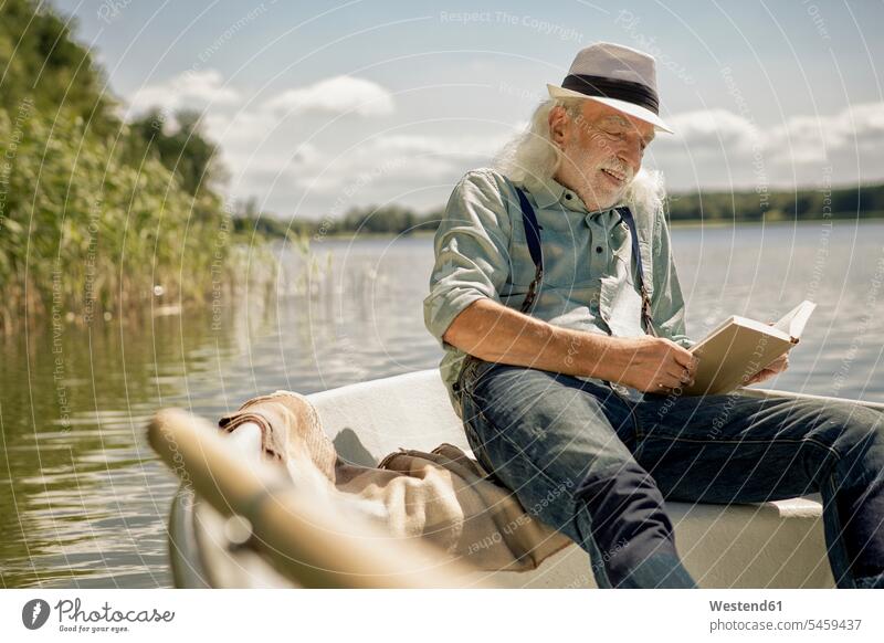 Porträt eines zufriedenen älteren Mannes, der in einem Ruderboot auf einem See sitzt und ein Buch liest Bücher Portrait Porträts Portraits Senior ältere Männer