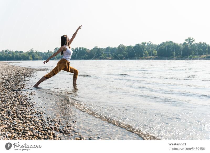 Junge Frau, die im Wasser eines Flusses steht und Yoga praktiziert stehen stehend weiblich Frauen Fluesse Fluß Flüsse Erwachsener erwachsen Mensch Menschen